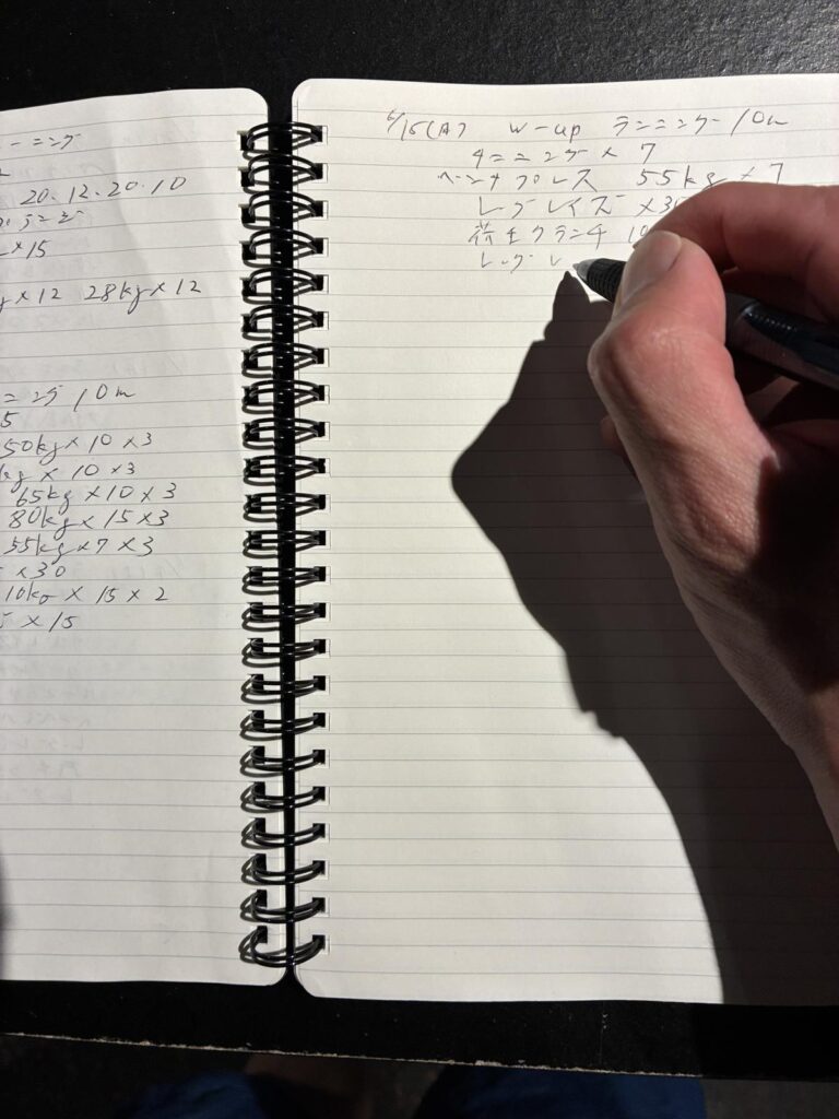 ノートにトレーニング内容を記録している手元|記録で続ける習慣づくり